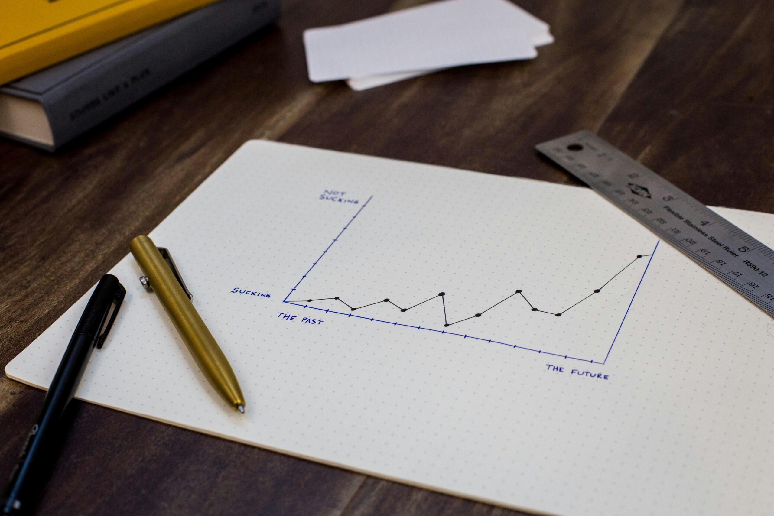 Close-up of a hand holding a pen over a lined notebook, capturing thoughts and ideas.